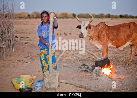 Dans le village Peul distant de Pete Goonga dans le nord du Burkina Faso, une femme livres millet pour la cuisson. Banque D'Images