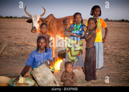 Ici, à la saison des pluies, village de Pete Goonga dans le nord du Burkina Faso, un groupe de femmes et d'enfants préparer le dîner au crépuscule. Banque D'Images