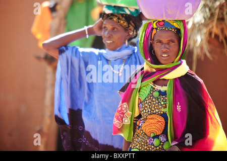 Deux femmes Fulani porter du lait frais pour les vendre au marché hebdomadaire de Djibo dans le nord du Burkina Faso. Banque D'Images