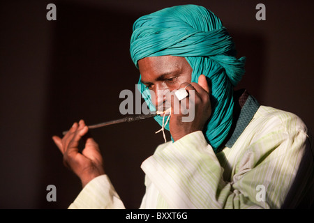 Un homme Peul d'un petit village dans le nord du Burkina Faso joue une flûte traditionnelle. Banque D'Images