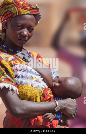Une femme allaite son enfant Peul dans le marché hebdomadaire de Djibo dans le nord du Burkina Faso. Banque D'Images