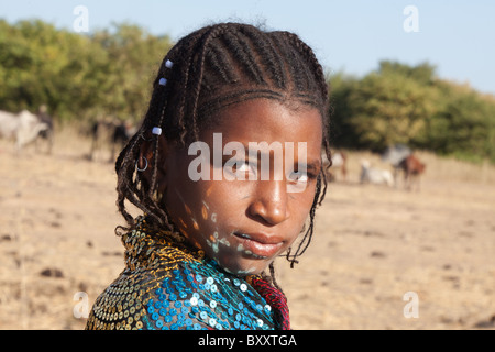 Dans un village peul de saison dans le nord du Burkina Faso, les réflexions des paillettes d'une jeune femme a la danse du châle sur son visage. Banque D'Images