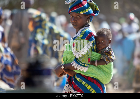 Dans le marché du village de Bourro, au nord du Burkina Faso, une femme Peul porte son fils sur son dos. Banque D'Images