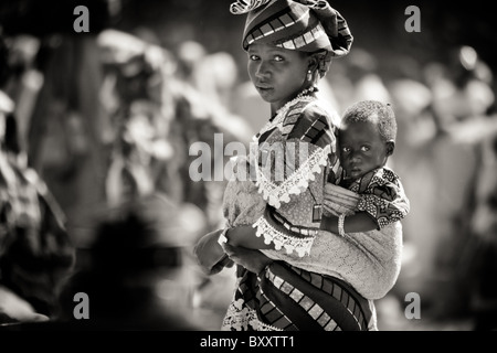 Dans le marché du village de Bourro, au nord du Burkina Faso, une femme Peul porte son fils sur son dos. Banque D'Images