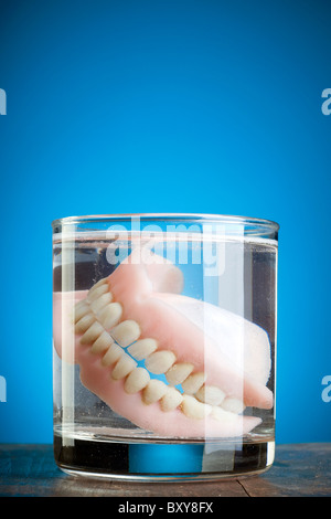 Une paire de dentier dans un verre d'eau Banque D'Images