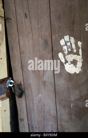 Une main blanche peint imprimer décore une vieille porte en bois rustique à un temple bouddhiste à Nong Kai, en Thaïlande. Banque D'Images