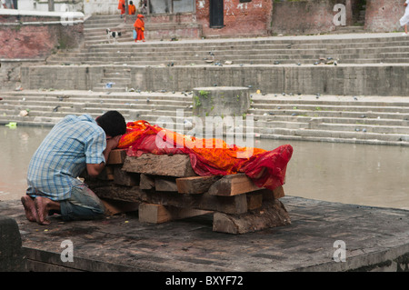 Un fils dit au revoir à un salon funéraire crémation sur la rivière Bagmati au Temple d'Pahsupatinath à Katmandou, Népal Banque D'Images