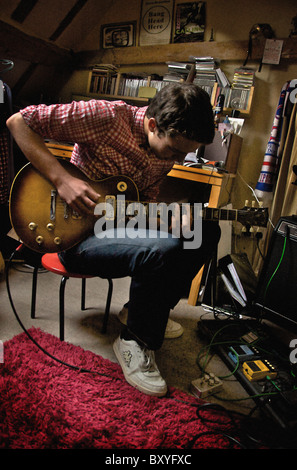 Hommes adolescents jouant Gibson guitare électrique dans la chambre Banque D'Images