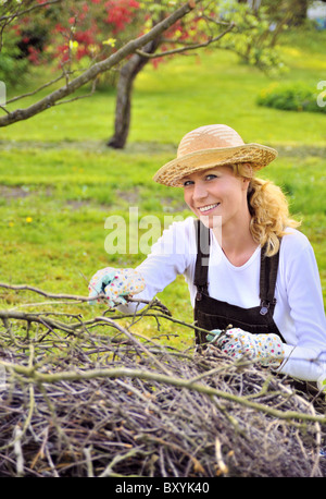 Jeune femme de branches d'arbres nettoyage Banque D'Images