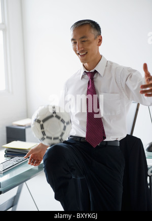 Kicking ball Smiling businessman in office Banque D'Images