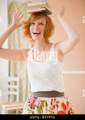 Portrait of young woman balancing books on head Banque D'Images