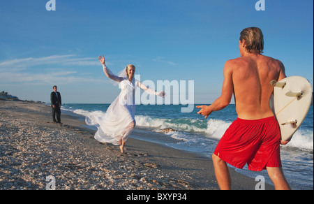 Jeune épouse tournant dans le bras de sauveteur sur la plage Banque D'Images