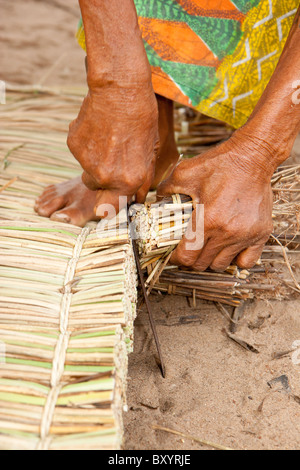 Une femme extra les garnitures de roseaux un matelas fabriqué à la main en Afrique de l'ouest dans le cadre d'un projet générateur de revenu géré par une ONG. Banque D'Images