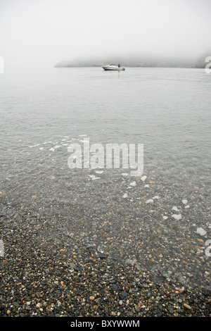 Bateau près de foggy beach Banque D'Images