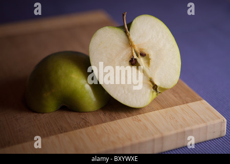 Couper Granny Smith apple sur une planche à découper en bois Banque D'Images