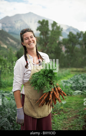 Portrait of woman holding carrots in field Banque D'Images