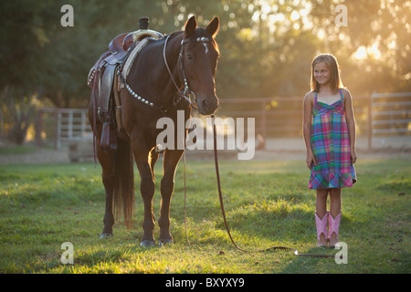 Girl standing à cheval en paddock Banque D'Images