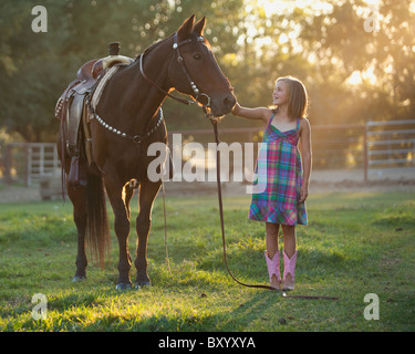 Fille de caresser dans l'enclos de chevaux Banque D'Images