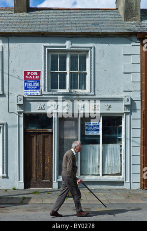 Vieil homme déambule passé Murphy shop avec agent immobilier à vendre dans les conseils, Kilkee, comté de Clare, à l'ouest de l'Irlande Banque D'Images