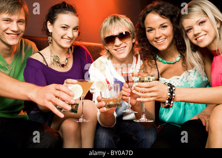 Portrait des jeunes en contact avec les verres les uns avec les autres à la discothèque Banque D'Images