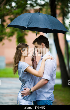Portrait de couple dans l'amour à l'extérieur sous parapluie et regarder Banque D'Images