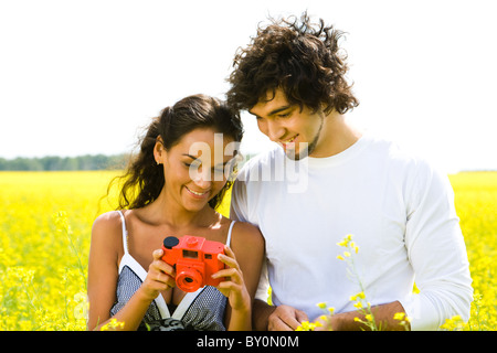 Portrait of happy guy looking at camera photo dans les mains de la jeune fille debout près de par Banque D'Images