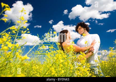Avis de couple amoureux à golden meadow sous ciel d'été avec des nuages sur elle Banque D'Images