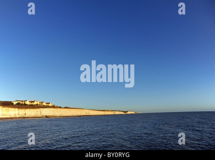 Filles Roedean school et les falaises de craie blanche en dessous prennent une lueur jaune comme le soleil commence à définir Banque D'Images