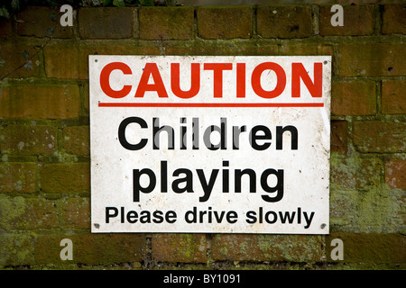 Inscription Attention enfants jouant Veuillez conduire lentement Banque D'Images