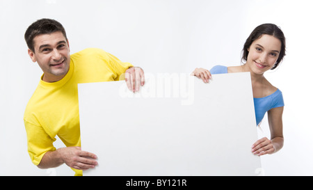 Smiling couple holding blank poster et photo sur fond blanc Banque D'Images