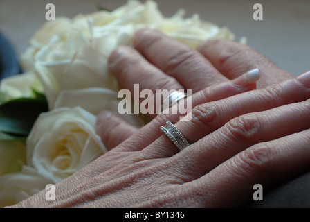 Mariée et le Marié mariage le jour de leur mariage en appui sur le bouquet de fleurs. Banque D'Images