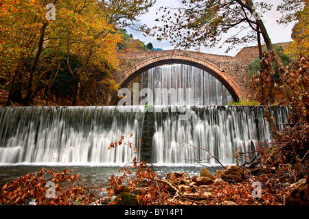 Un vieux pont voûté en pierre, entre deux cascades dans Paleokarya, préfecture de Trikala, Thessalie, Grèce Banque D'Images