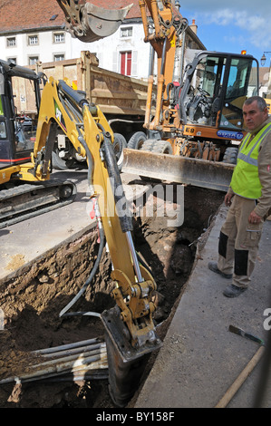 Contrôle ouvrier de l'équipement d'excavation du trou d'excavation en route pour réparer les câbles d'alimentation Saulieu France Banque D'Images