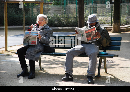 Les personnes lisant le journal sur banc de parc Paris France Banque D'Images