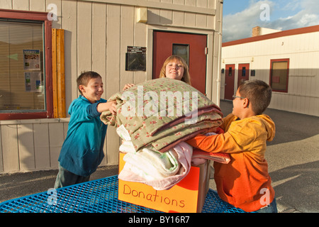 Les enfants de l'école intermédiaire age 11-12 ans ans collecter des couvertures aux personnes qui ont moins de chance enfant enfants aidant M. © Myrleen Pearson Banque D'Images