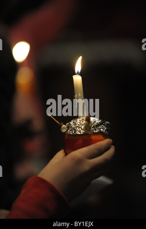 Une jeune fille est titulaire d'un Christingle allumé au cours d'un service carol la veille de Noël à St Peter's Collegiate Church, Wolverhampton Banque D'Images