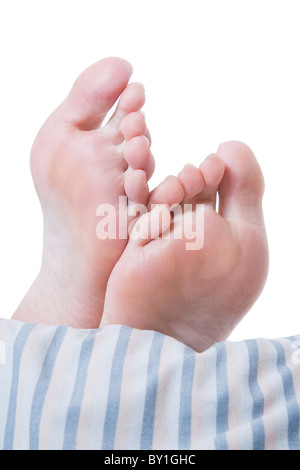 Pieds de la femme qui sort de l'extrémité de son lit avec une couette à rayures,nice Banque D'Images