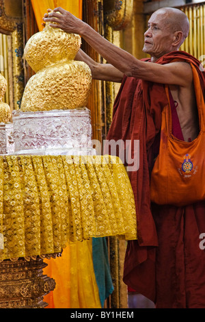 Le Myanmar, Birmanie, lac Inle. Un moine s'applique la feuille d'or à l'un des cinq images de Bouddha, aujourd'hui transformé en un blob par la seule Banque D'Images