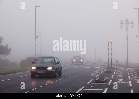 Voitures circulant en milieu urbain avec le marquage routier en un jour brumeux avec éclairage sur Banque D'Images