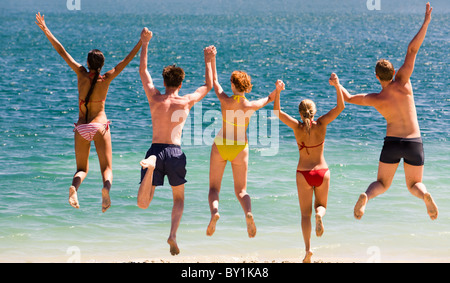Photo d'adolescents en sautant à la mer se tenant par les mains Banque D'Images