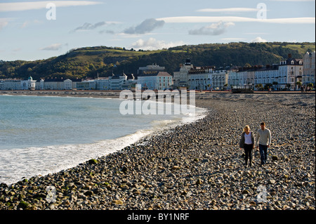 Llandudno. Un couple marche le long de la plage de galets sur le front de mer de la station balnéaire victorienne de Llandudno. (MR) Banque D'Images