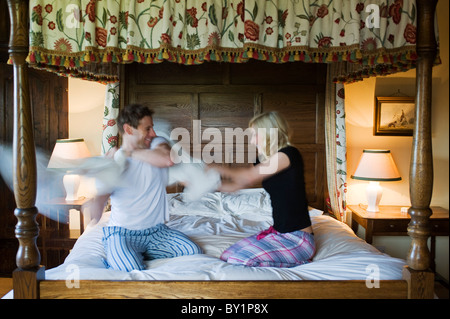 Ferme Gilar, Snowdonia, Nord du Pays de Galles. Un couple lutte contre l'oreiller et s'amuser sur le lit à baldaquin dans la chambre à coucher principale. (MR) Banque D'Images