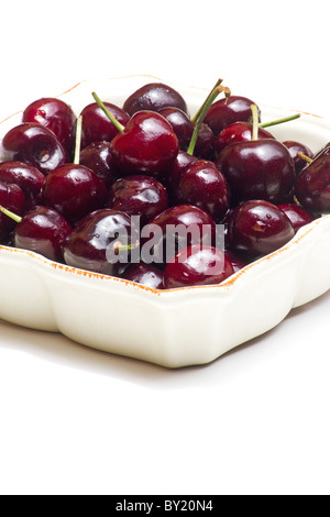 Close-up de cerises fraîches dans un bol sur fond blanc Banque D'Images