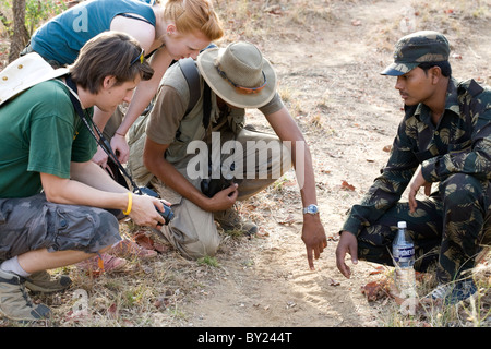 L'Inde, le Madhya Pradesh, le Parc National de Satpura. Un guide souligne sloth bear tracks d'un jeune couple sur un safari à pied. Banque D'Images