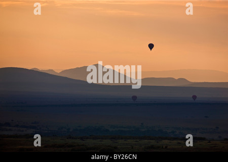 Au cours de l'aube comme Masai-Mara montgolfières dérive sur les plaines. Banque D'Images