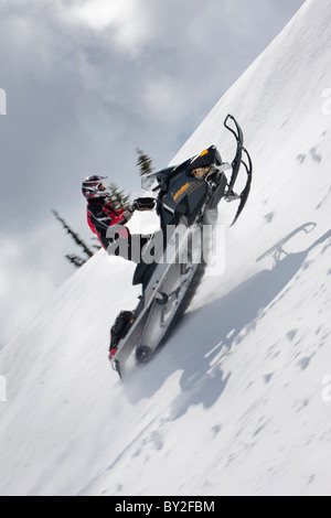 Un homme obtient un peu d'air en roulant sur une motoneige sur le côté de la montagne Owlshead. Banque D'Images