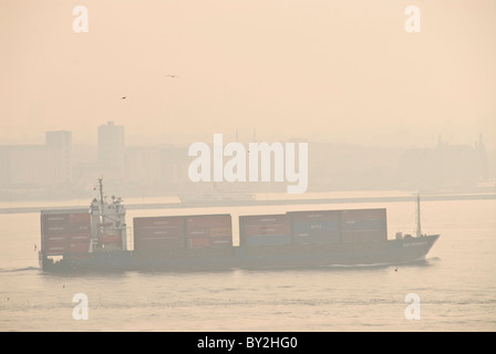 ISTANBUL, Turquie / Türkiye / Türkiye — Un grand cargo traverse l’étroite intersection de la mer de Marmara, de la Corne d’Or et du détroit du Bosphore, passant très près de la côte à Istanbul, en Turquie. Le Bosphore, une voie navigable vitale reliant la mer Noire à la mer de Marmara, offre des scènes étonnantes d'Istanbul avec ses monuments historiques et son activité maritime animée. Ce détroit emblématique divise la ville en deux côtés européens et asiatiques, avec de magnifiques palais, mosquées et ponts au bord de l'eau. Banque D'Images