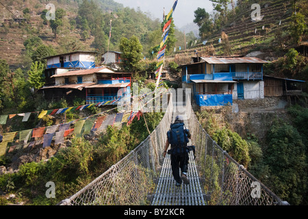 Un jeune homme marche sur un pont suspendu à Tikhedunga, de l'Annapurna Himalaya, Népal. Banque D'Images