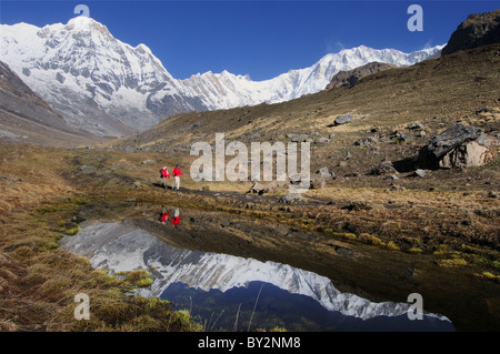 Les randonneurs et les sommets de l'Annapurna reflétée dans un lac dans le sanctuaire de l'Annapurna Banque D'Images