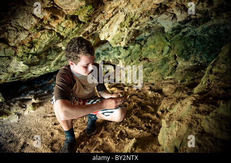 Un jeune homme regarde les dépôts de chert dans une grotte sur l'île Santa Cruz de Santa Barbara, CA. Banque D'Images